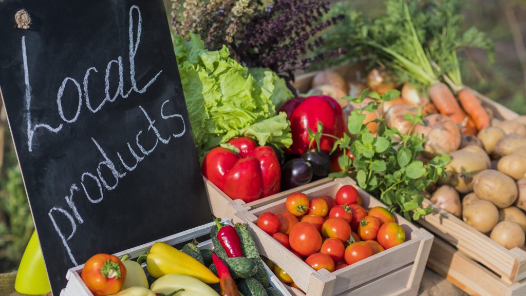Chalk sign amid vegetables advertising local produce