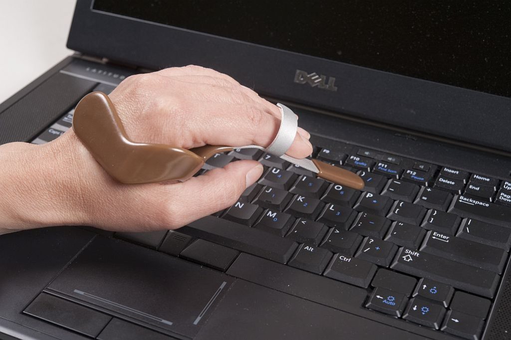 Close up of a person's hand using a specialized device to type on a keyboard