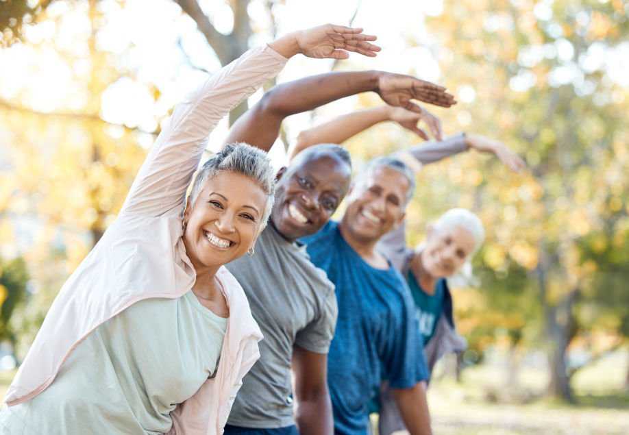 Senior people in a park doing some stretches and a workout, smiling at the camera